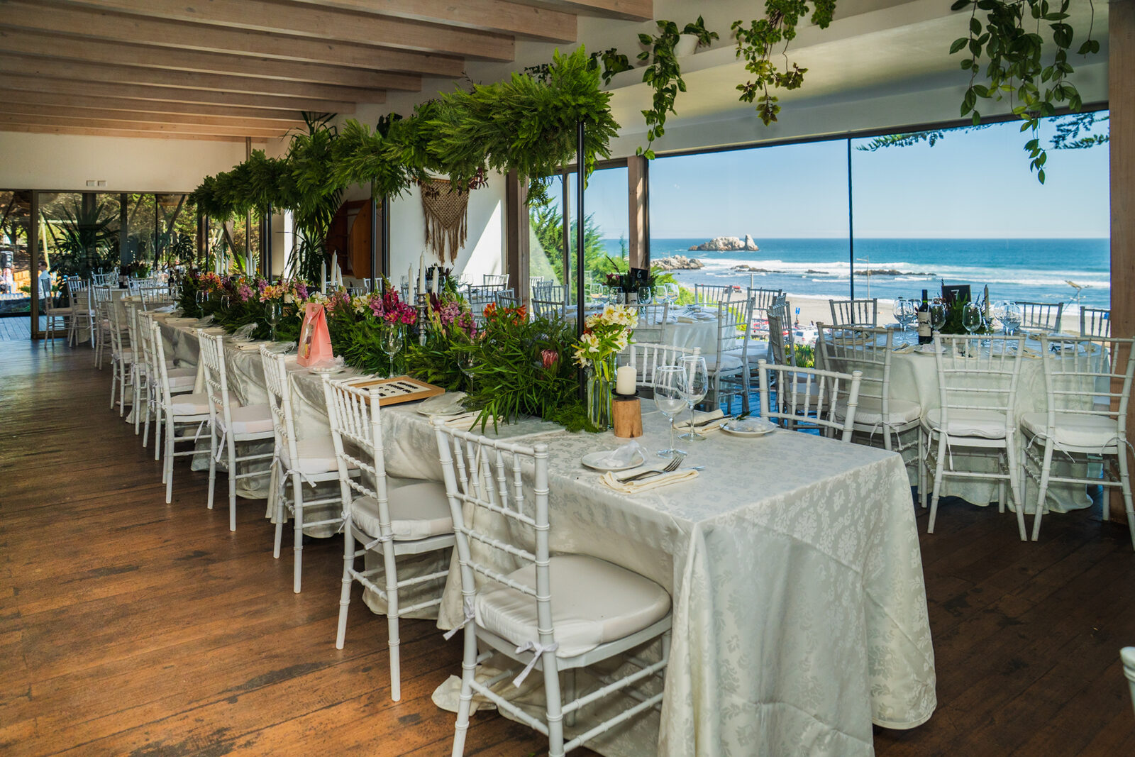Mesa larga decorada con flores y vista al oceano